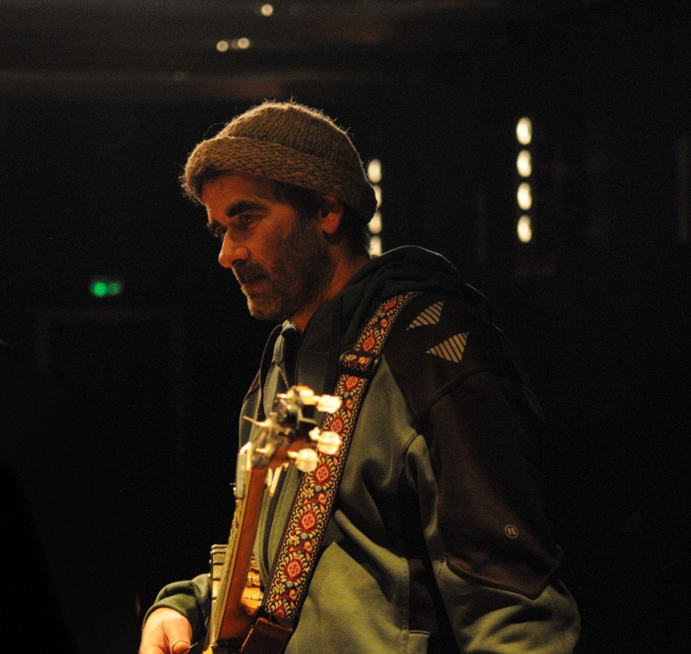 Le banjoïste, bonnet de laine et sangle brodée, concentré avant de jouer.