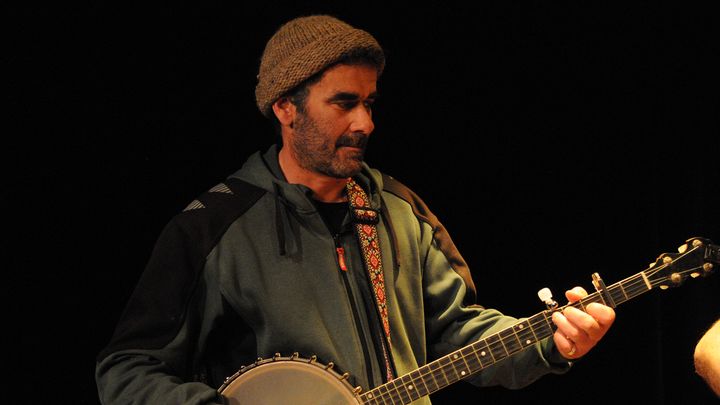Le banjoïste au banjo, devant le rideau noir.