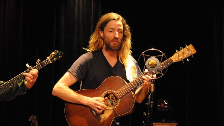 Le guitariste chante devant le micro.