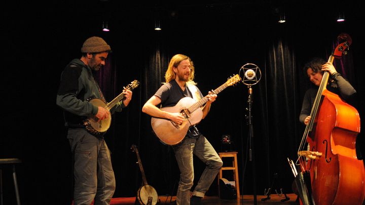 Le trio sur scène, le guitariste esquisse un pas de danse.