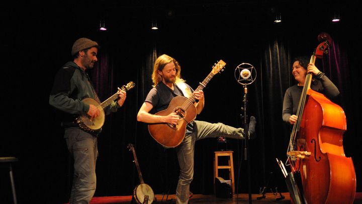 Le guitariste lance la jambe, la contrebassiste éclate de rire.